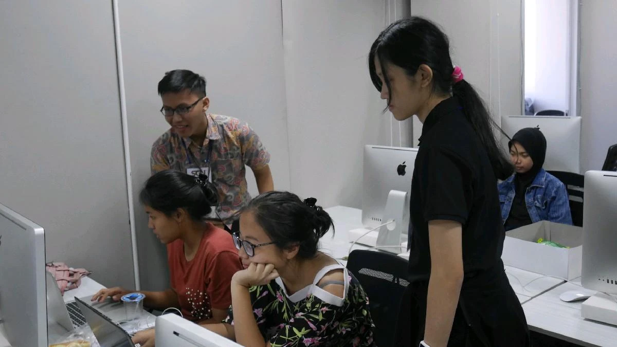 Jonathan Suhangita mentoring students at computers during the Swiss German University summer coding course