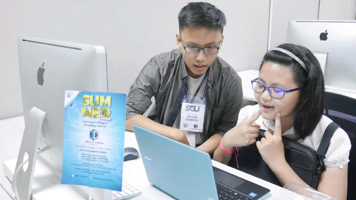 Jonathan Suhangita, wearing an SGU lanyard, mentoring a student at the summer coding course