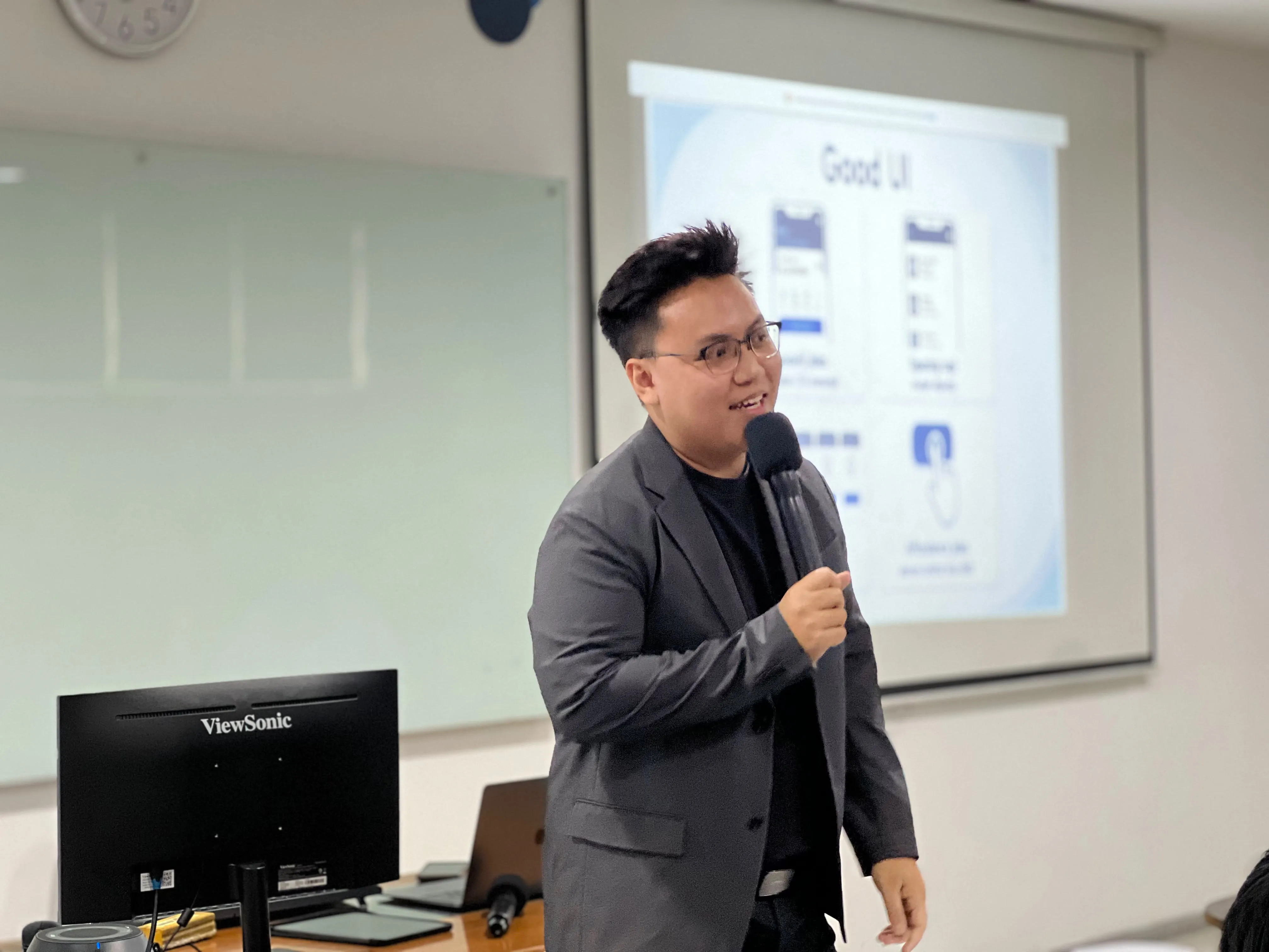 Jonathan Suhangita presenting a Good UI lecture with a microphone at UKRIDA